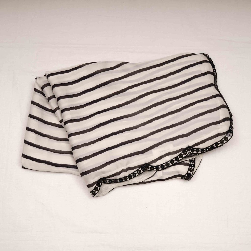 Crisp white designer saree with intricate thread embroidery, sequin embellishments, and premium fabric showcasing handcrafted elegance